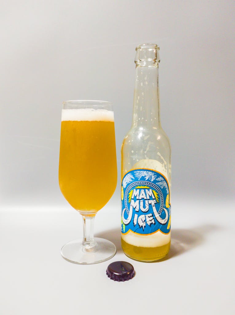 Chilled craft beer in glass and bottle displaying Mammut Ice label on a white background.