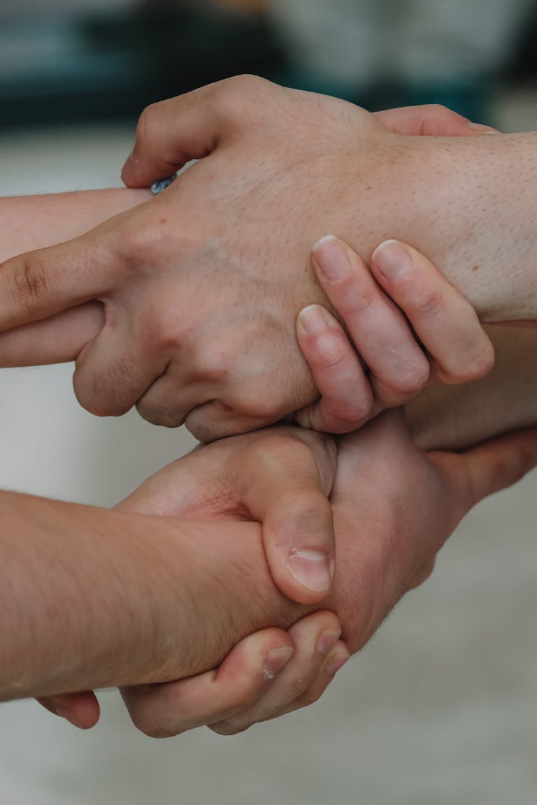 A close-up of three hands holding each other, symbolizing unity and diversity.